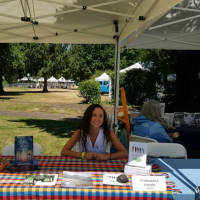 Francesca Varela sitting at a table outside at a book event in Eugene, Oregon.