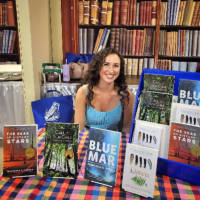 Francesca sitting at a table signing books at the Oregon State Fair in Salem, Oregon.