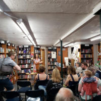 Francesca Varela standing at a podium during a book reading.