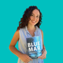 Francesca Varela holding up her novel, Blue Mar