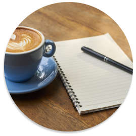 Coffee mug on a table next to a notebook