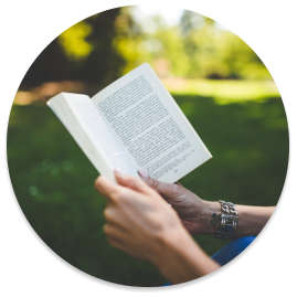 Person reading a book outside in the grass