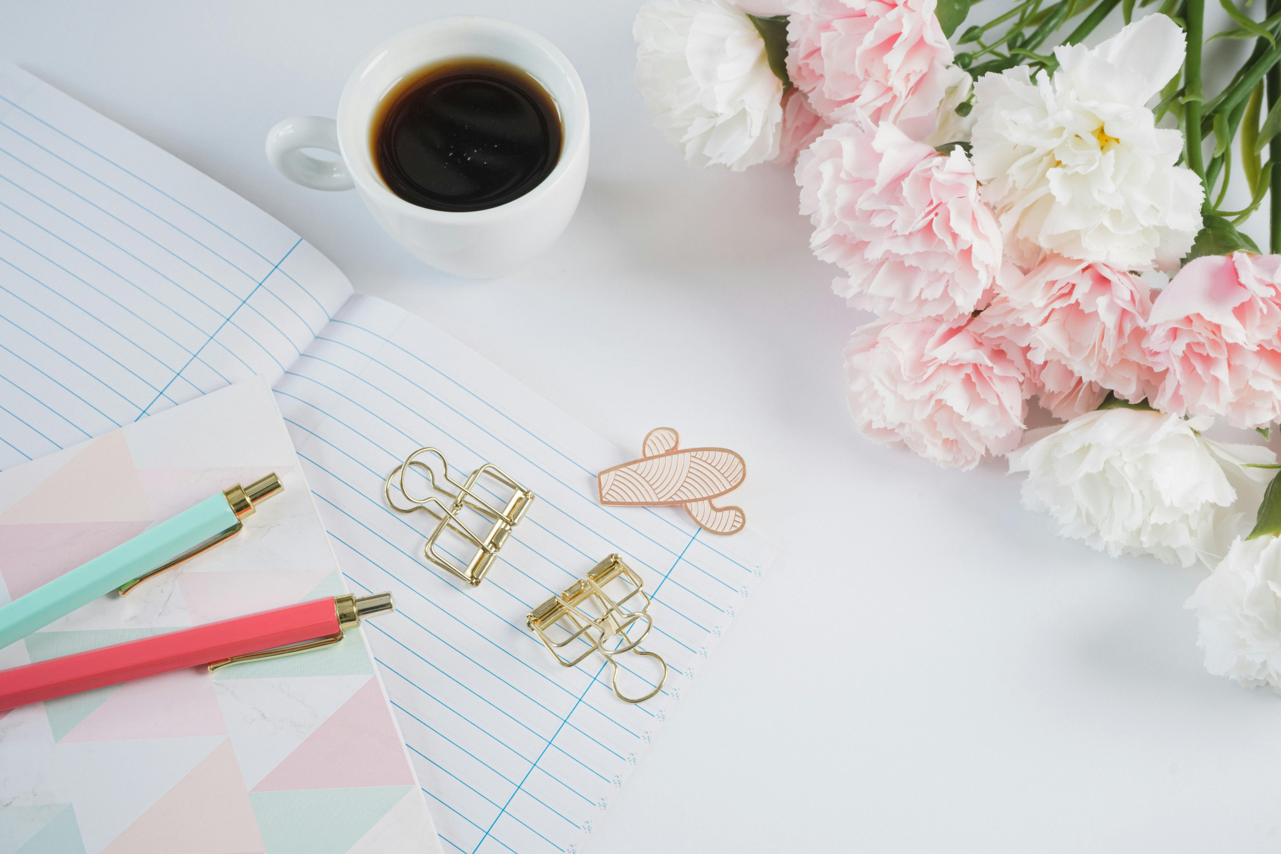White desk with flowers and notebook, which Francesca Varela uses to copy edit for indie authors